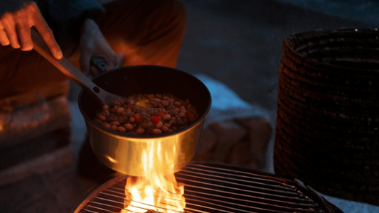 Person cooking beans & beef over an open fire