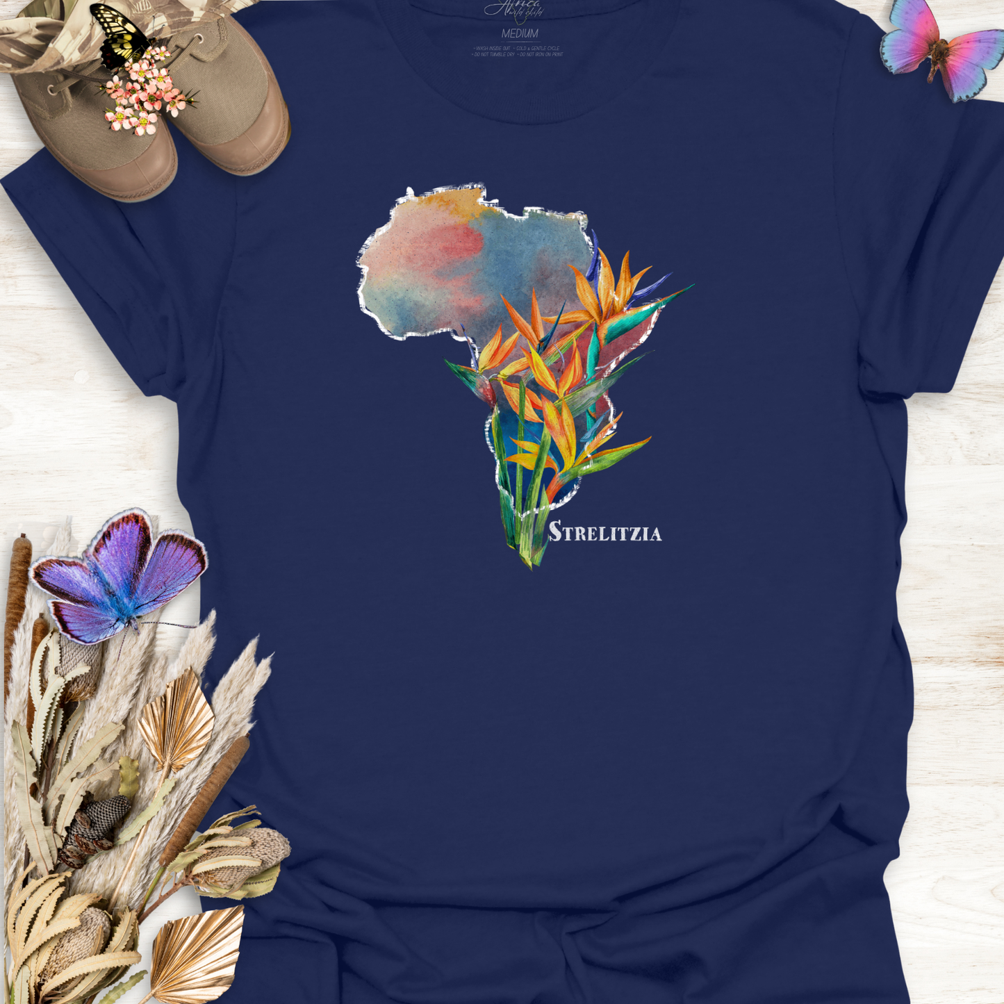 Navy Blue t-shirt with a colorful graphic of Africa and Strelitzia flowers on a wooden surface.