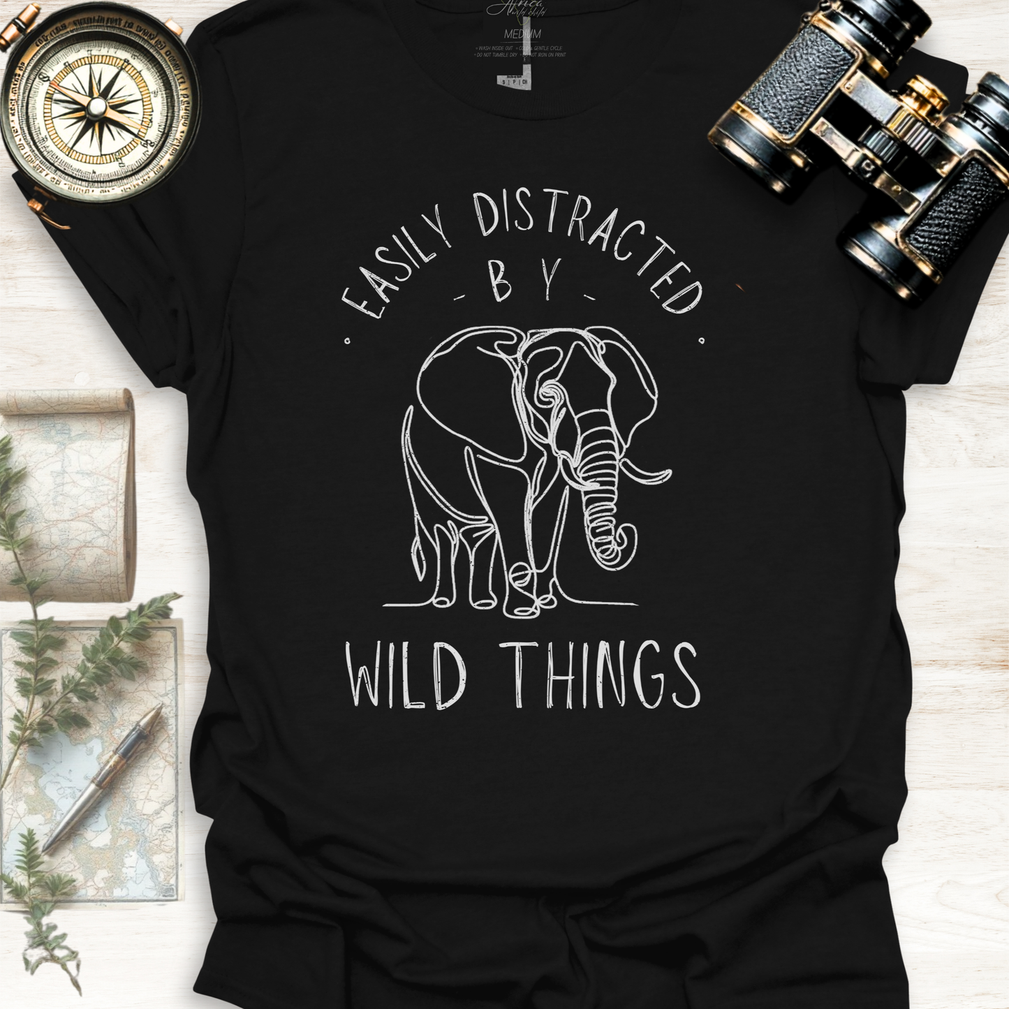 Black wildlife graphic t-shirt with white elephant graphic and text 'Easily Distracted by Wild Things, outdoor lifestyle apparel by Africa Wild Child.