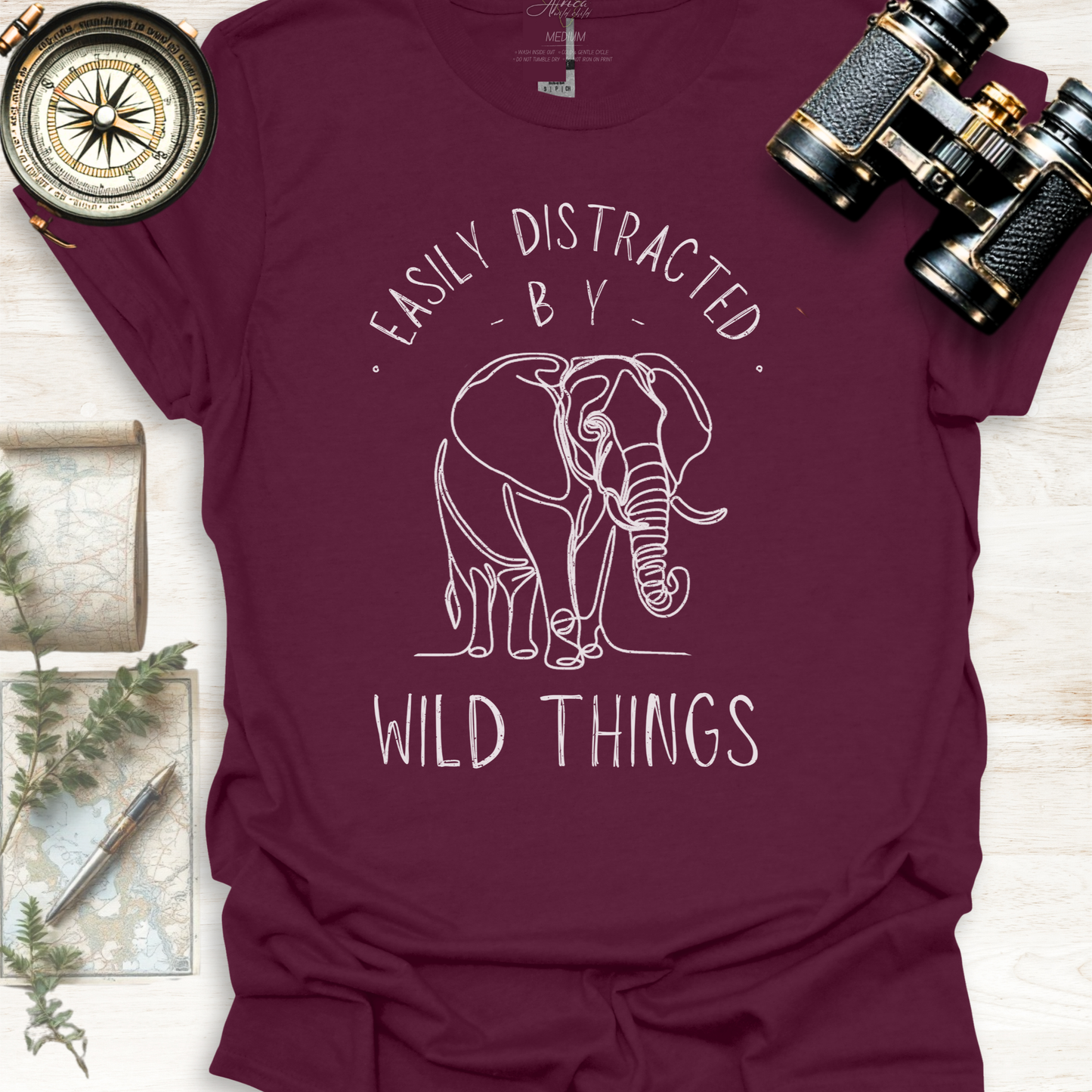Maroon wildlife graphic t-shirt with white elephant graphic and text 'Easily Distracted by Wild Things, outdoor lifestyle apparel by Africa Wild Child.