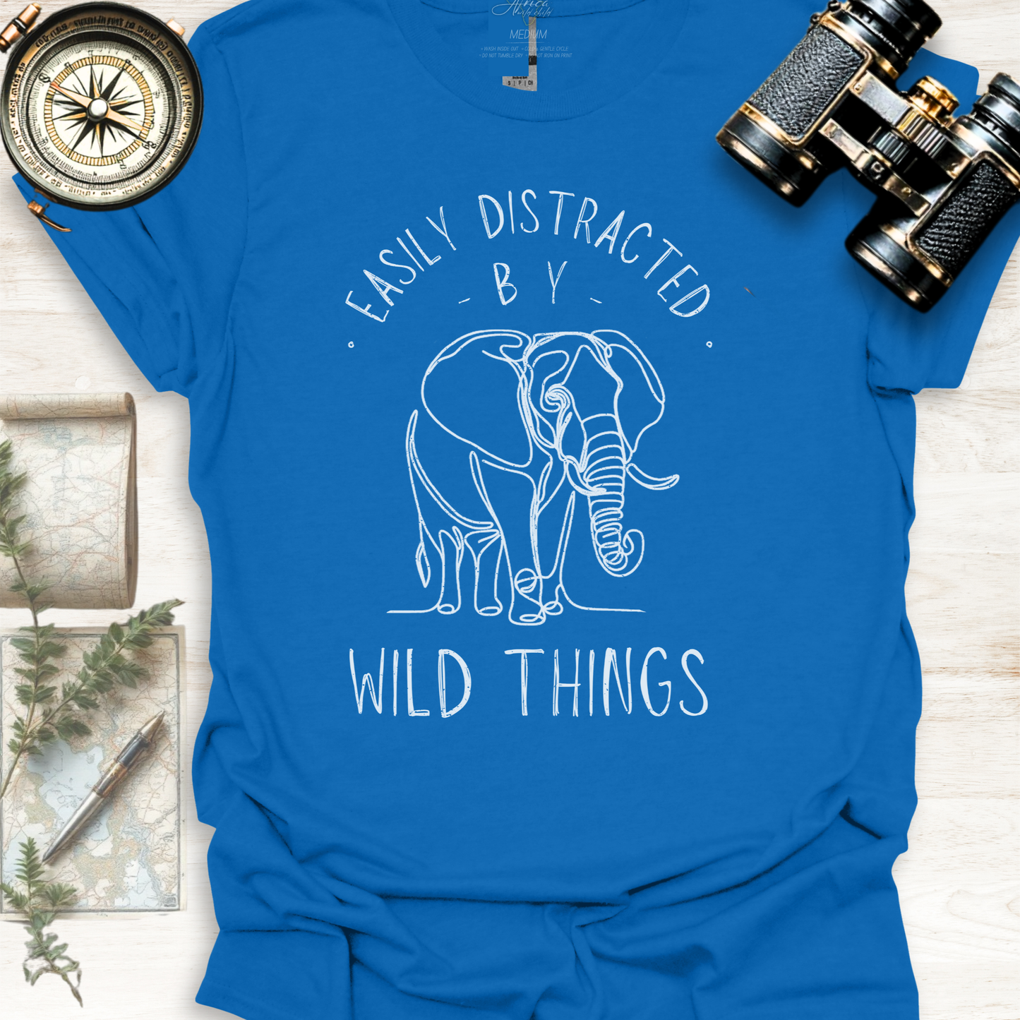 Light blue wildlife graphic t-shirt with white elephant graphic and text 'Easily Distracted by Wild Things, outdoor lifestyle apparel by Africa Wild Child.